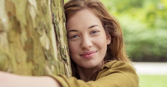 Frau Umarmt baum mit for a greener planet Schriftzug