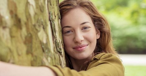 Frau Umarmt baum mit for a greener planet Schriftzug